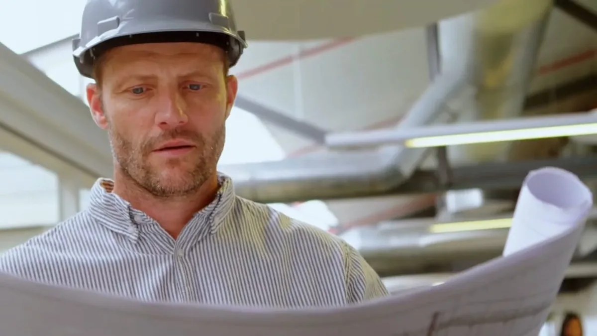 Plumber in a hard hat explaining a pipe fitting for Fountain Valley Plumbing Blog in Fountain Valley